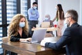 Businesswomen wear masks and typing on laptops and looking to his colleague who wears black suit discusses work in the modern Royalty Free Stock Photo