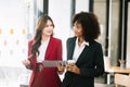 Businesswomen work and discuss their business plans. A Human employee explains and shows her colleague the results paper in modern Royalty Free Stock Photo