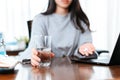 Businesswomen working at home with glass of water takes white round pill in hand