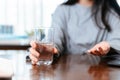 Businesswomen working at home with glass of water takes white round pill in hand