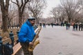 Busker playing saxophone while other passersby pass around him