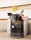 Busker singing and playing guitar inside a rubbish bin