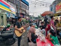 a busker singing a song next to visitors to the culinary market in Pasar Lama, Tangerang, Indonesia city