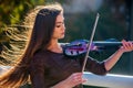 Busker woman perform music on violin park outdoor. Girl performing .