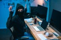 busted hacker in mask with raised hands in front