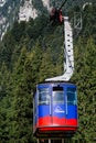 BUSTENI, ROMANIA - AUGUST 2, 2017: Blue cable car cabin transports tourists from Busteni resort up to Bucegi Mountains plateau, Royalty Free Stock Photo