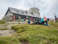 Busteni/Romania - 08.22.2020: Crowded weekend day on Omu Peak, the highest peak in Bucegi Mountains. Man lying on the grass and Royalty Free Stock Photo