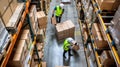 the bustling activity within a warehouse as workers navigate among towering shelves filled with cardboard boxes, seen Royalty Free Stock Photo