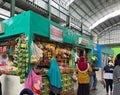 bustling atmosphere in a traditional market with a stall full of groceries and several buyers