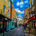 Bustling city street with a variety of shops, restaurants, and pedestrians walking along it.