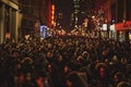 A bustling crowd of people walking down the street at night, filled with revelers and activity, A bustling crowd of revelers in