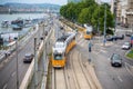 Bustling street scene with a variety of cars on the road and a train in Budapest, Hungary.