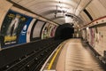 subway station featuring a long platform with large-scale advertisements on the walls in London