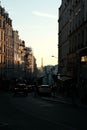 Bustling urban scene with a line of cars driving down a street lined with buildings in Paris, France