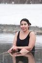 Busty curvy plus size young adult model in black one-piece bathing suit sitting in pool at spa Royalty Free Stock Photo