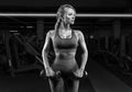 Busty girl in a tracksuit posing in the gym with dumbbells. Fitness concept. Black and white Royalty Free Stock Photo