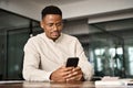 Busy African American entrepreneur using cell phone working in office.