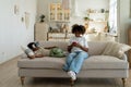 Busy african american mother use smartphone while little son watching movie with VR glasses at home
