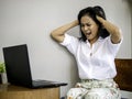 Busy asian business woman seriously looking problem in work at computer, she has on idea holding the head with hand with headache Royalty Free Stock Photo