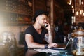 Busy behind the bar. Shot of a young man using a phone and laptop while working in a coffee shop. Royalty Free Stock Photo