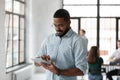 Busy black manager standing at office focused on tablet screen