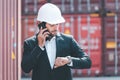 Busy business man, engineer manager wearing white hardhat, looking at his wristwatch, checking the time while standing in front of Royalty Free Stock Photo