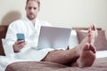 Busy businessman working on laptop and reading message on phone Royalty Free Stock Photo