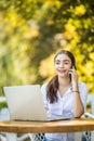 Busy businesswoman talking on mobile phone sitting at the cafe table with laptop Outdoors Royalty Free Stock Photo