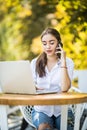 Busy businesswoman talking on mobile phone sitting at the cafe table with laptop Outdoors Royalty Free Stock Photo