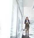 Busy businesswoman walking to her office holding files and drinking coffee. One female lawyer carrying documents and a