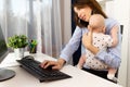 Busy businesswomen working at a office with a baby on her hands. Royalty Free Stock Photo