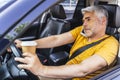 Busy Caucasian man with cupholder in arm is driving his car