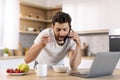 Busy cheerful married millennial caucasian guy with beard eats porridge, calls by phone, enjoys good morning