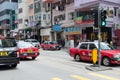 Busy city life, day traffic on the street, a lot of car and red taxi on road, people on the sidewalk