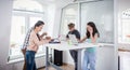 Busy co-workers using mobile technology while sharing a desk in a work hub