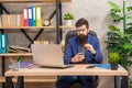 busy confident bearded boss study online on laptop hold coffee in the office, modern life