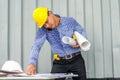 Busy construction engineer talking on phone while carrying blueprints with checking the building progress