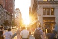 Busy crowds of people walking down the sidewalk on 23rd Street in New York City with sunlight background