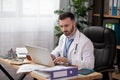 Young bearded doctor looking involved working on laptop Royalty Free Stock Photo