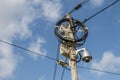 Busy electricity line and security camera against blue sky.