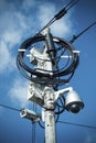 Busy electricity line and security camera against blue sky.