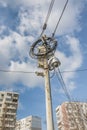 Busy electricity line and security camera against blue sky.