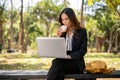 A busy, elegant Asian businesswoman is working remotely on her laptop in a park while having lunch Royalty Free Stock Photo