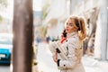 Busy elegant woman hurrying down the street and looking back with smile. Wonderful business-lady with cute ponytail