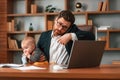 Busy father. Businessman in formal clothes is working indoors. With toddler Royalty Free Stock Photo