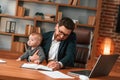 Busy father. Businessman in formal clothes is working indoors. With toddler Royalty Free Stock Photo