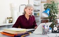 Busy focused aged female entrepreneur working with papers and laptop