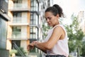 Busy freelancer woman checking time on hands watch while resting in city, sitting on a street wooden bench during coffee break Royalty Free Stock Photo