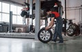 Busy guy. Mechanic holding a tire at the repair garage. Replacement of winter and summer tires Royalty Free Stock Photo