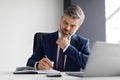 Busy Handsome Middle Aged Businessman Writing In Notepad While Sitting In Office Royalty Free Stock Photo